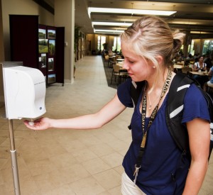A student takes a squirt of disinfectant from the dispenser in the Market Place. Gustavus has added more electric hand-sanitizers to combat the spread of the flu. Photo by: Alex Messenger