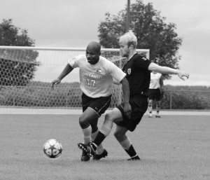 Senior defender Abdul Suleyman wards off a St. Olaf player, while trying to protect the ball.  Sports Information.