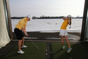 Sophomore McKenzie Swenson, on the right, hits balls into the snow in the Drenttel Golf Facility.