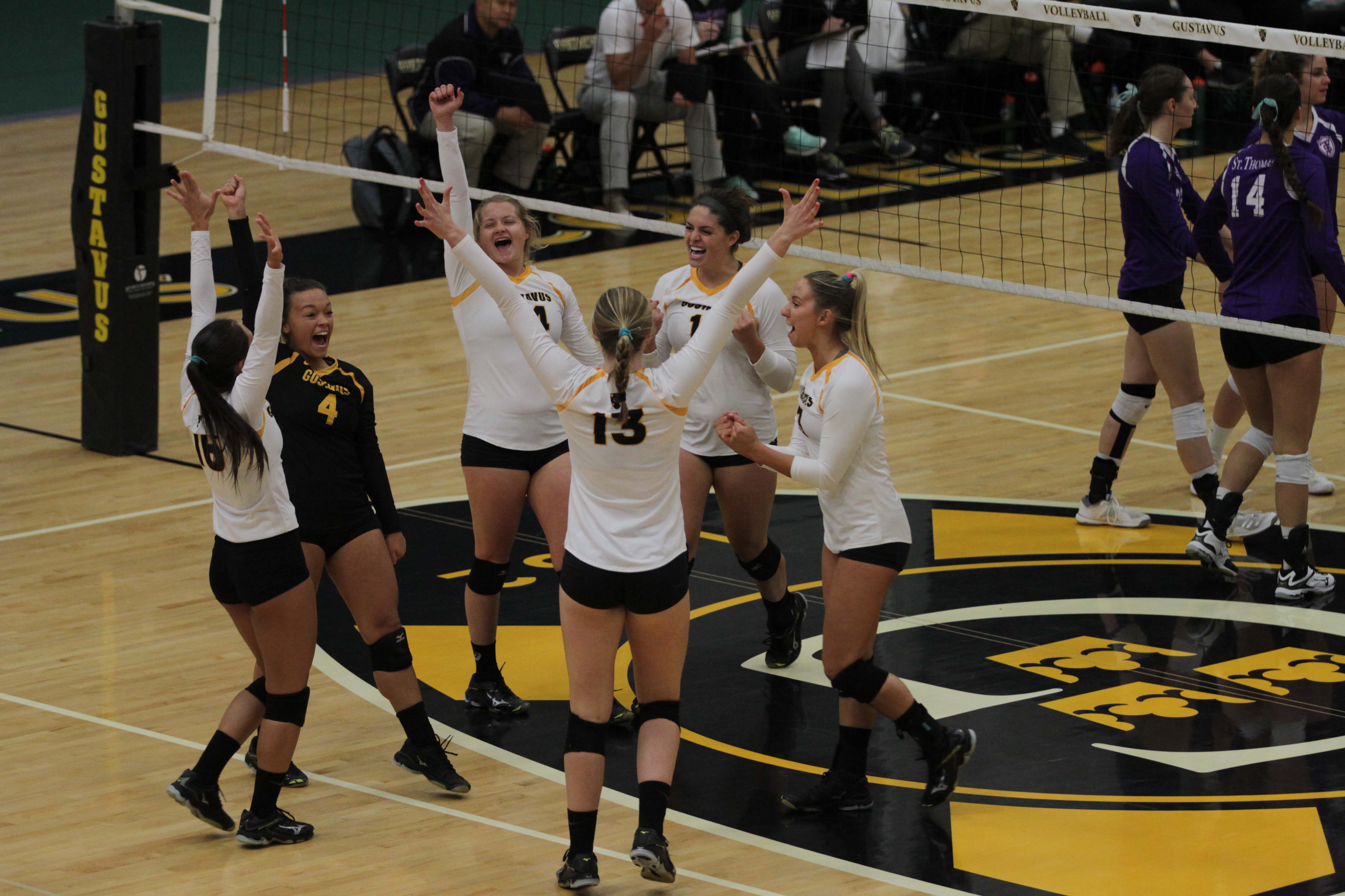 The Gustavus Women's Volleyball team celebrates on the court.