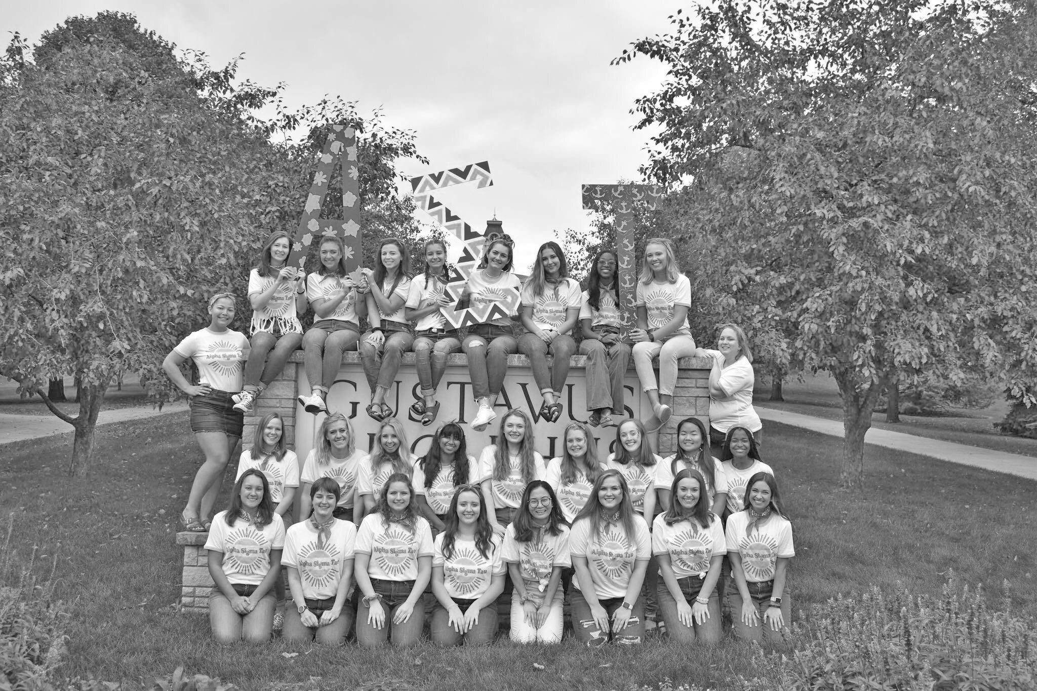 The Alpha Sigma Tau sorority gathered on the Gustavus sign for a photo.